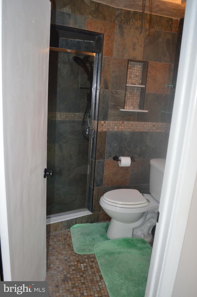 bathroom featuring tiled shower and toilet