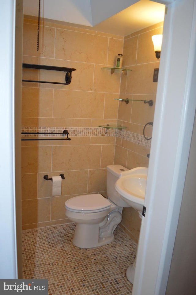 bathroom with tile walls, tile patterned flooring, sink, and toilet