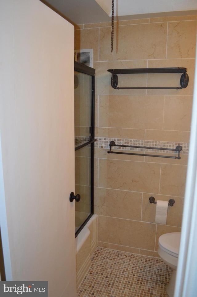 bathroom featuring toilet, tile patterned flooring, and shower / bath combination with glass door