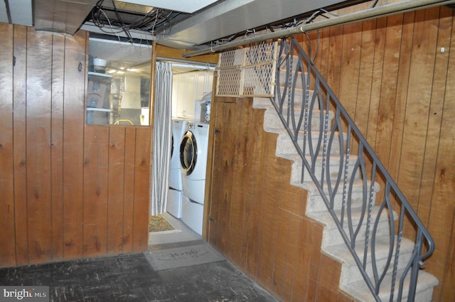 clothes washing area featuring washer and dryer and wooden walls