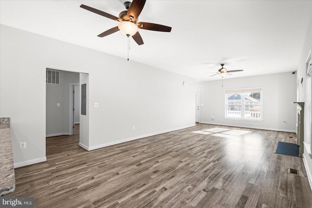 unfurnished living room with hardwood / wood-style floors, ceiling fan, and a stone fireplace