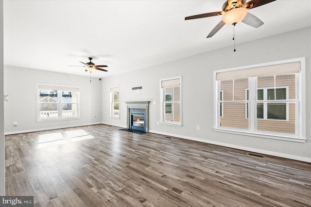 unfurnished living room with a high end fireplace, ceiling fan, and dark hardwood / wood-style flooring