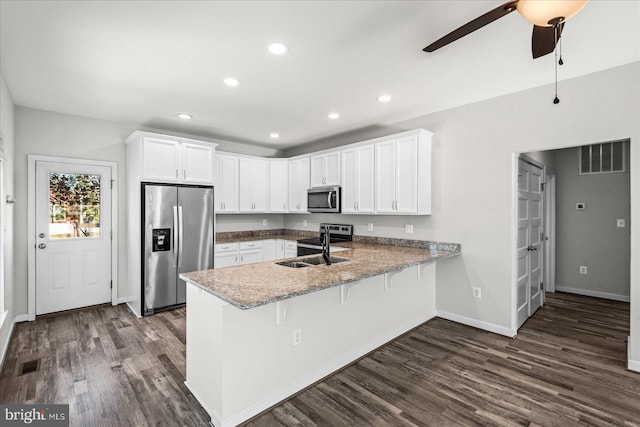 kitchen with stainless steel appliances, sink, white cabinets, light stone counters, and kitchen peninsula