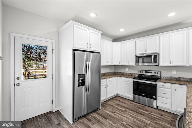 kitchen featuring stainless steel appliances, white cabinetry, dark stone countertops, and dark wood-type flooring