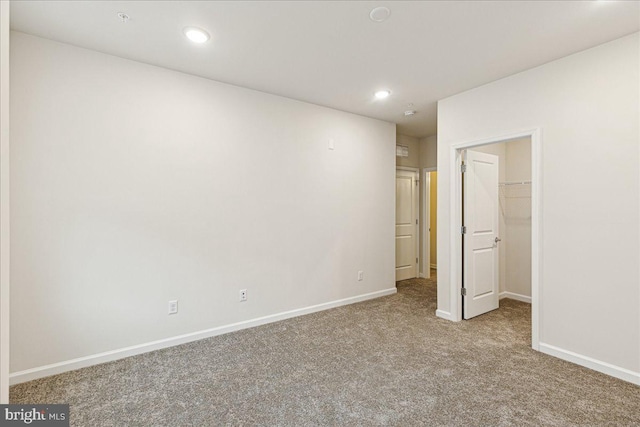 unfurnished bedroom with a walk in closet, a closet, and light colored carpet