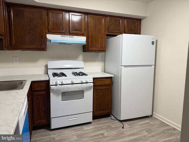 kitchen with light hardwood / wood-style flooring, white appliances, and sink