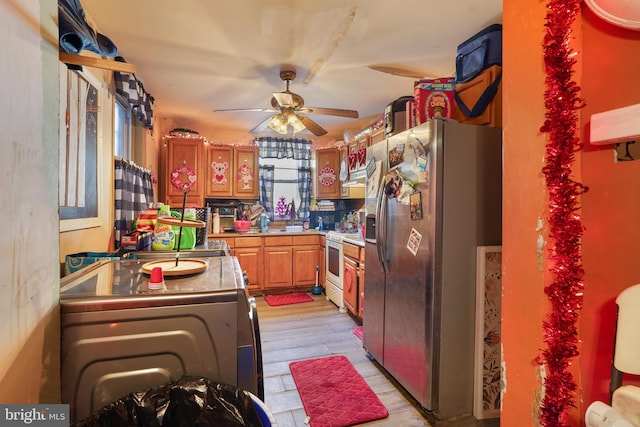 kitchen with light wood-type flooring, stainless steel fridge, white stove, and ceiling fan