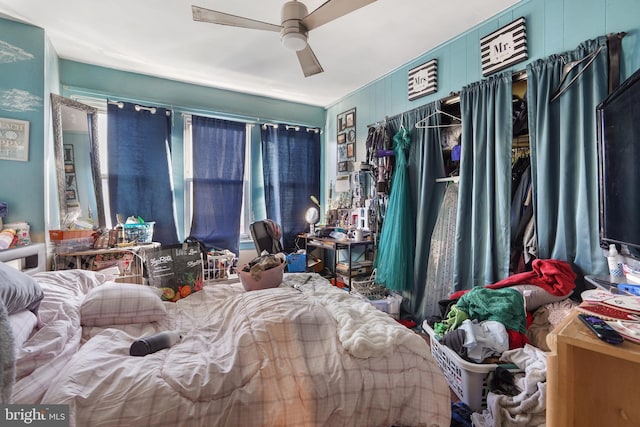 bedroom featuring ceiling fan and wood walls