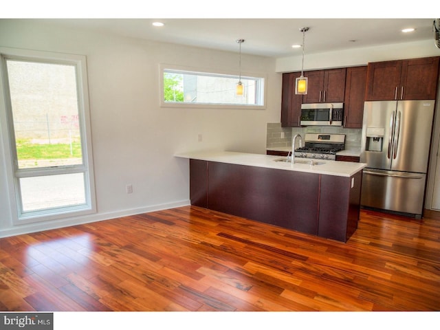 kitchen featuring backsplash, dark wood-type flooring, pendant lighting, and stainless steel appliances