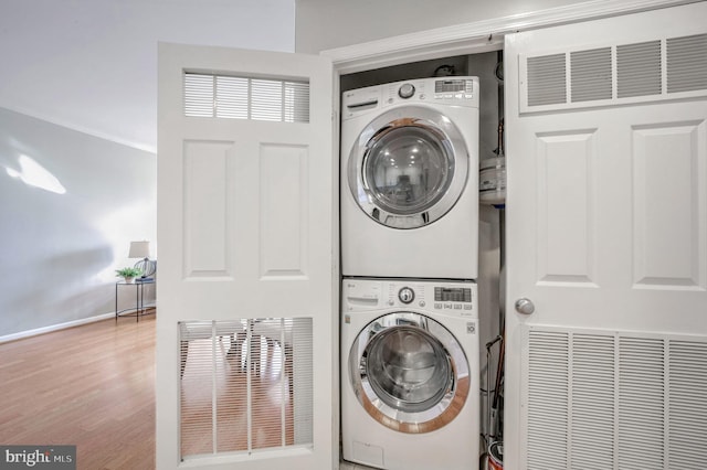 laundry area with hardwood / wood-style flooring and stacked washer and clothes dryer