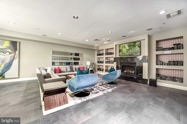 living room featuring a tiled fireplace and built in features