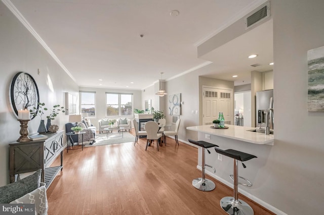 living room with sink, light wood-type flooring, and crown molding