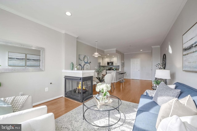 living room featuring a multi sided fireplace, hardwood / wood-style floors, ceiling fan, and crown molding