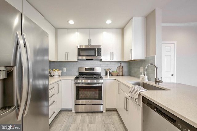 kitchen with tasteful backsplash, sink, white cabinets, and stainless steel appliances