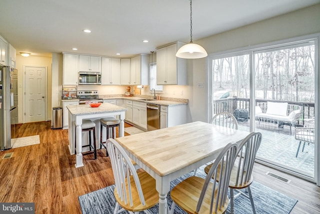 kitchen with sink, hanging light fixtures, appliances with stainless steel finishes, and white cabinets