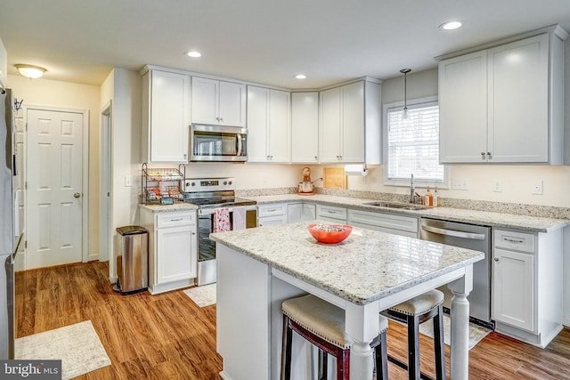 kitchen featuring sink, stainless steel appliances, hanging light fixtures, and white cabinets