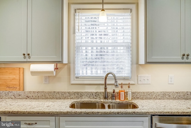 kitchen with sink, dishwasher, light stone counters, and hanging light fixtures