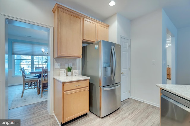 kitchen with tasteful backsplash, appliances with stainless steel finishes, light brown cabinets, and light hardwood / wood-style flooring