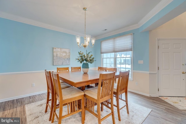 dining room with an inviting chandelier, ornamental molding, and light hardwood / wood-style flooring