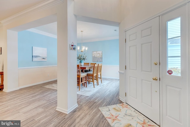 entrance foyer with ornamental molding, a notable chandelier, and light wood-type flooring