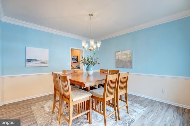 dining room featuring light wood-type flooring, an inviting chandelier, and ornamental molding