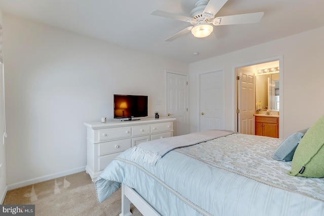 bedroom featuring ceiling fan, light colored carpet, and connected bathroom