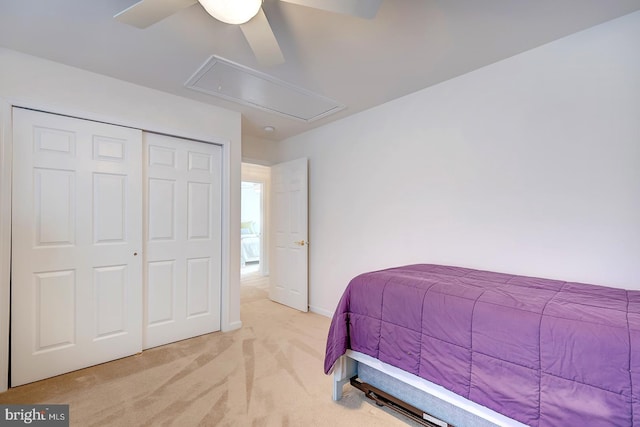 bedroom with ceiling fan, light colored carpet, and a closet