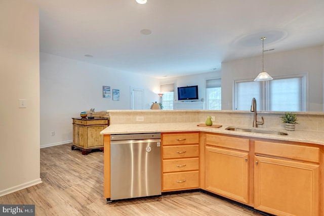 kitchen featuring light wood-type flooring, decorative light fixtures, stainless steel dishwasher, and sink