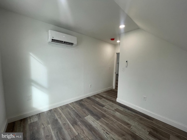 empty room featuring an AC wall unit, dark wood-type flooring, and vaulted ceiling