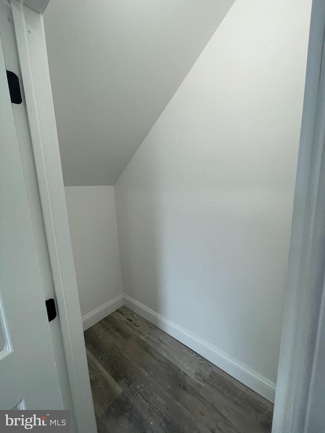 bonus room with vaulted ceiling and dark wood-type flooring