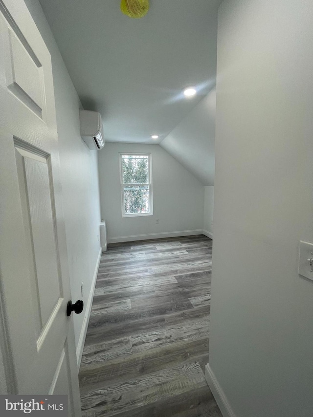 bonus room featuring lofted ceiling, radiator heating unit, dark hardwood / wood-style floors, and a wall mounted air conditioner