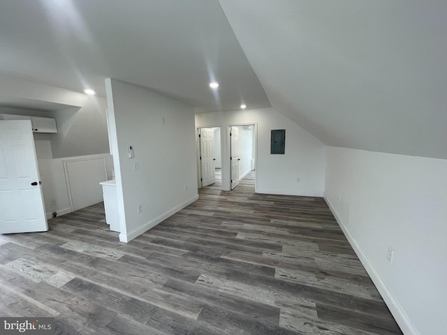 additional living space with electric panel, vaulted ceiling, and dark wood-type flooring