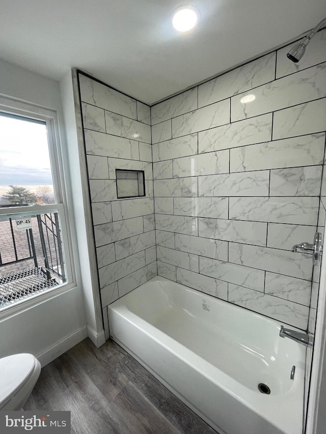 bathroom with toilet, tiled shower / bath, and hardwood / wood-style flooring