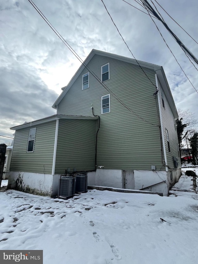 snow covered back of property featuring cooling unit