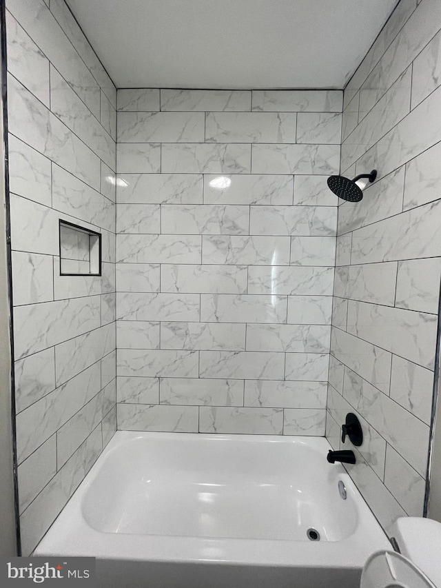 bathroom featuring tiled shower / bath combo and toilet