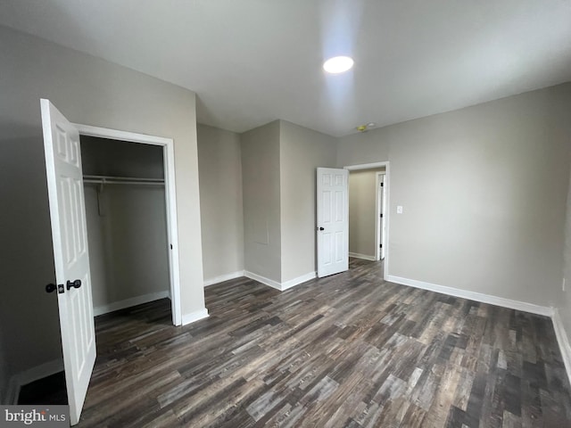 unfurnished bedroom with dark wood-type flooring and a closet