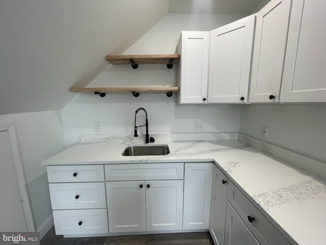 kitchen featuring light stone counters, sink, and white cabinets