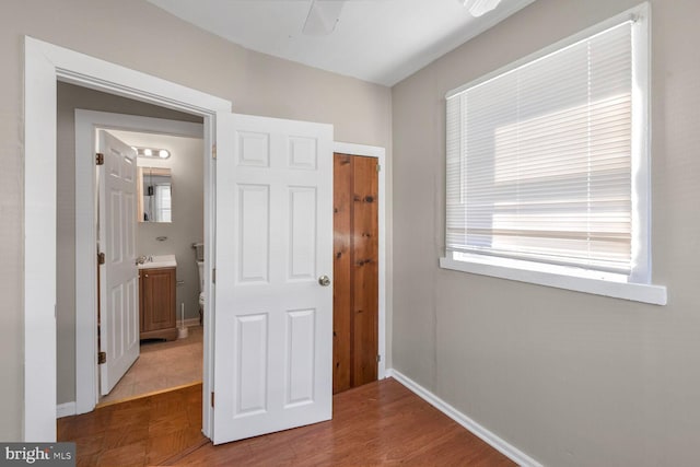 unfurnished bedroom featuring ensuite bathroom and hardwood / wood-style floors