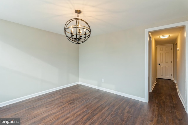 unfurnished room with dark hardwood / wood-style floors and an inviting chandelier