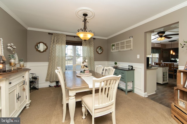 carpeted dining area with ornamental molding and ceiling fan