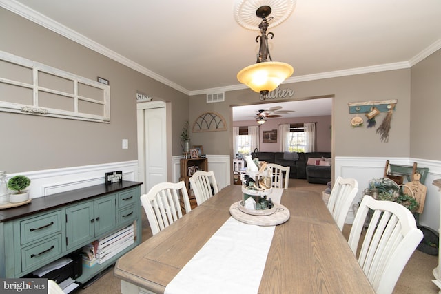 dining room with ceiling fan, ornamental molding, and light colored carpet