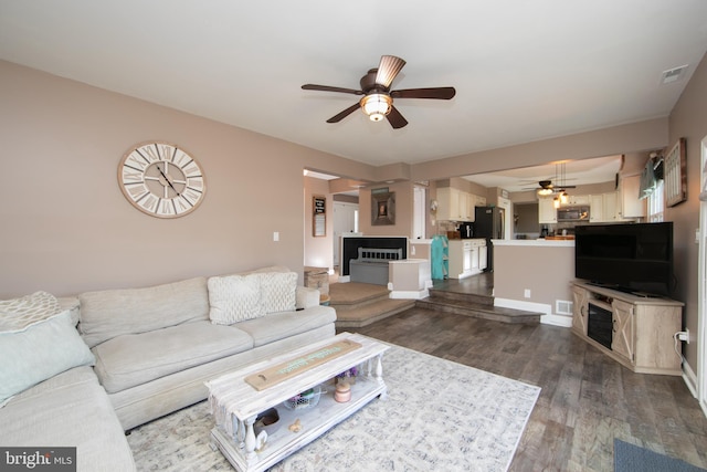 living room with ceiling fan and dark hardwood / wood-style flooring