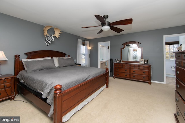 carpeted bedroom featuring ceiling fan, multiple windows, and ensuite bath