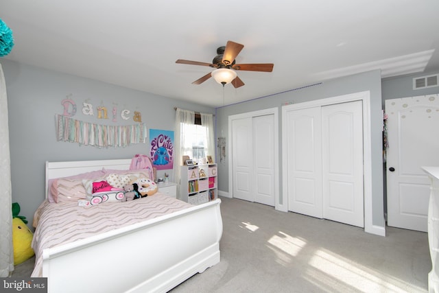 carpeted bedroom featuring ceiling fan and multiple closets