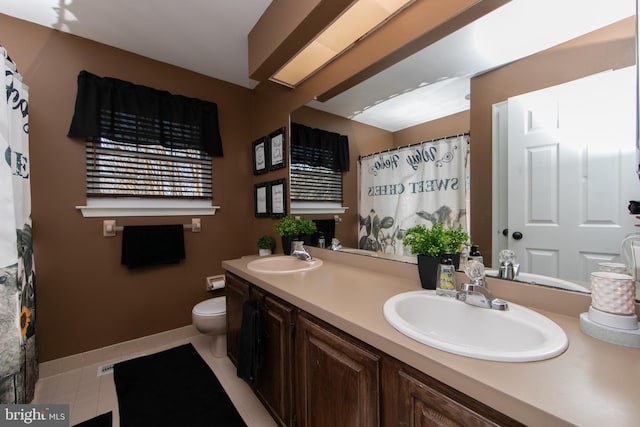 bathroom with toilet, vanity, and tile patterned floors