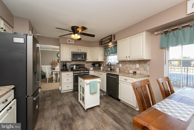 kitchen featuring stainless steel appliances, sink, backsplash, a kitchen island, and dark wood-type flooring