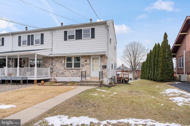 view of front of property featuring a front lawn, central air condition unit, and a porch