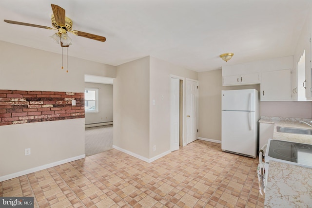 kitchen with baseboard heating, white cabinetry, white fridge, sink, and ceiling fan