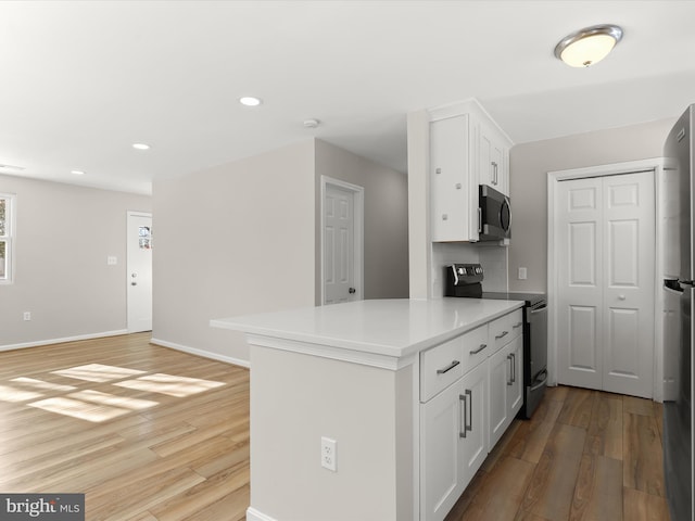 kitchen featuring white cabinets, appliances with stainless steel finishes, and hardwood / wood-style floors