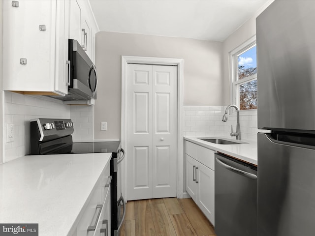 kitchen featuring sink, white cabinets, backsplash, and appliances with stainless steel finishes